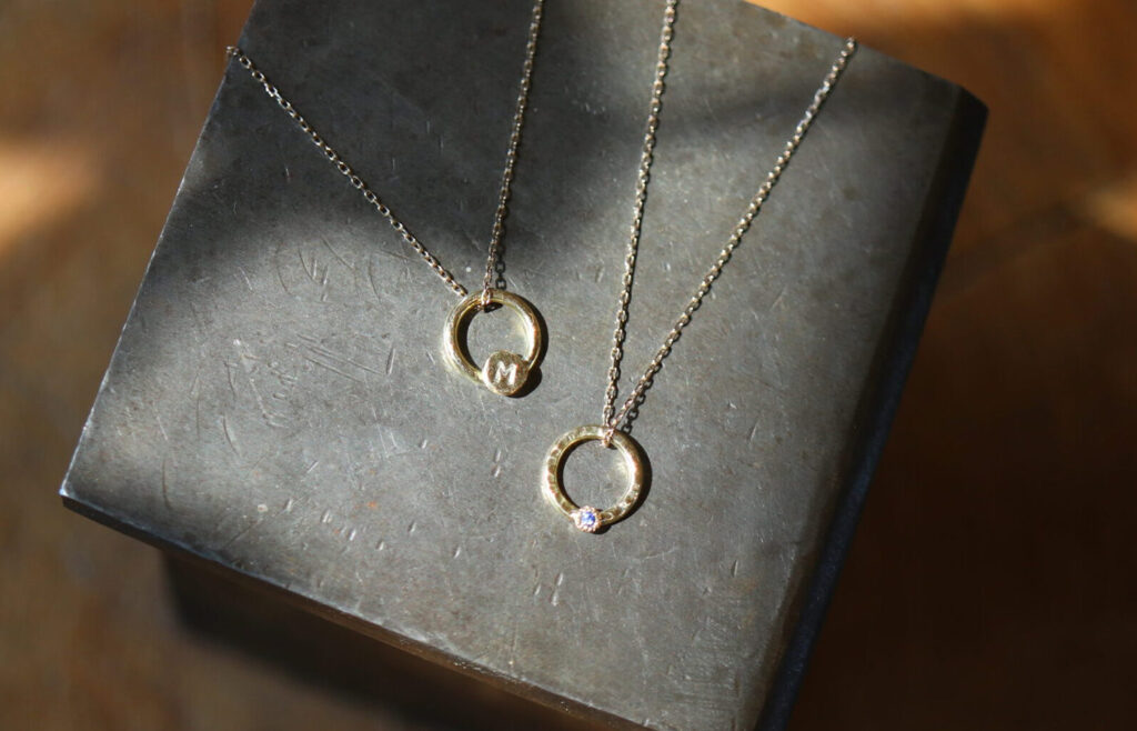 Two handmade 18K gold circle pendant necklaces with gemstone accents