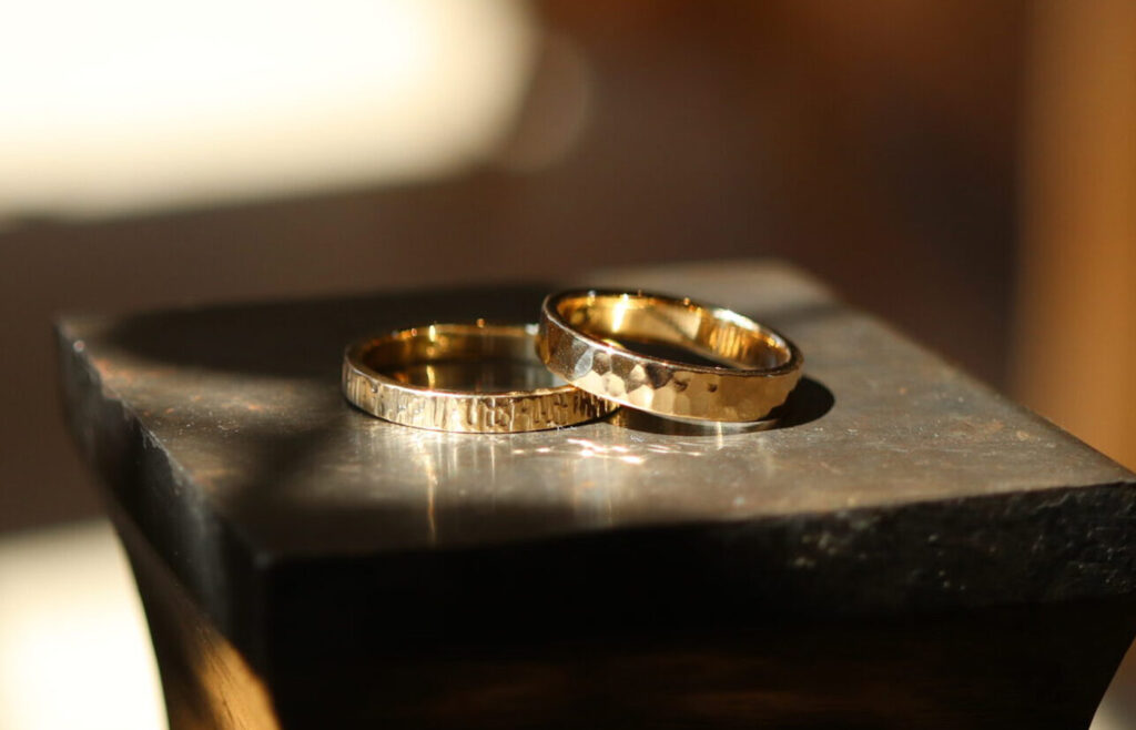 Pair of handmade 18K gold wedding rings with hammered and engraved finishes
